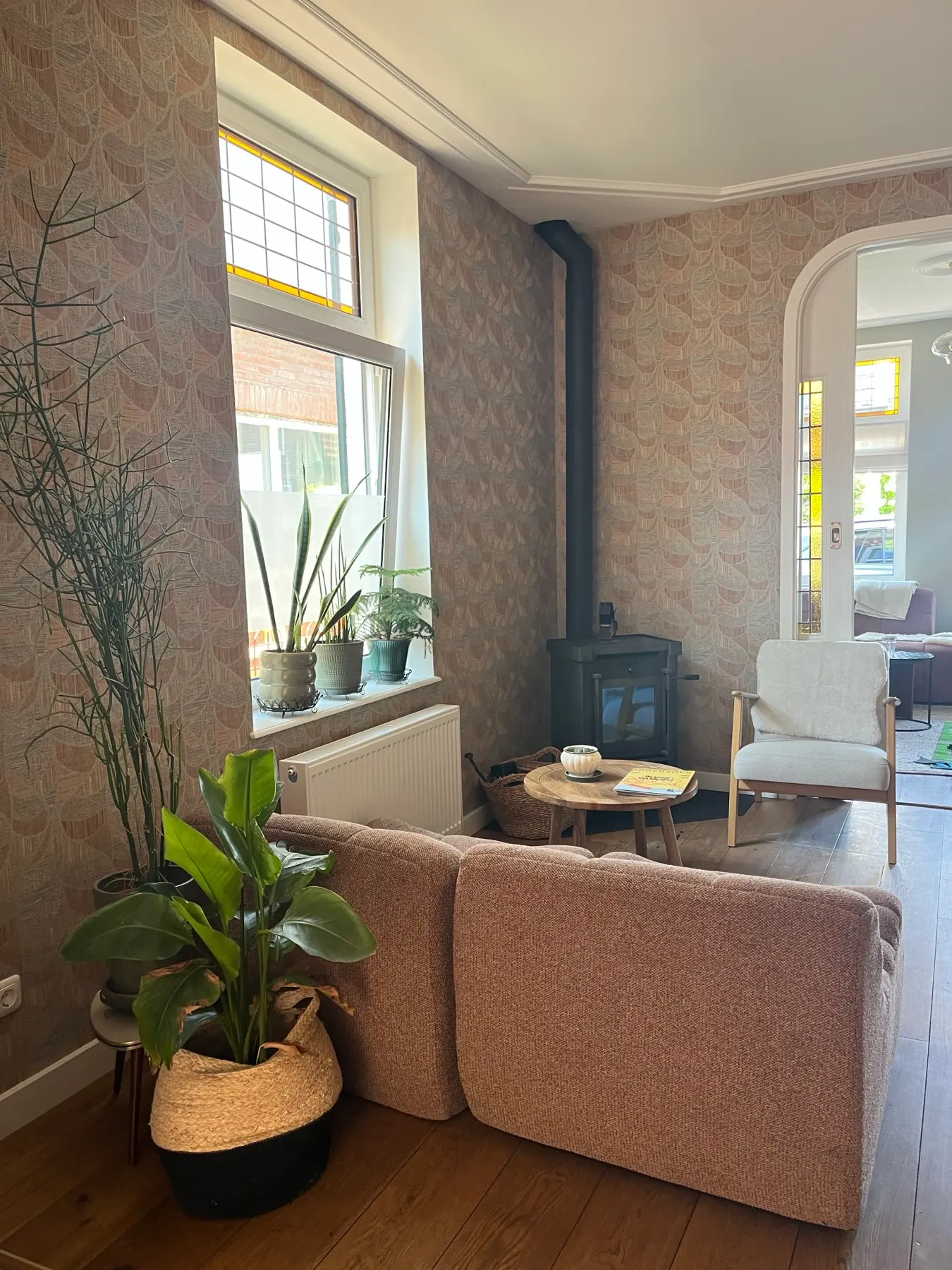 Woonkamer met dessinbehang, bouclé bank, houtkachel en glas-in-lood